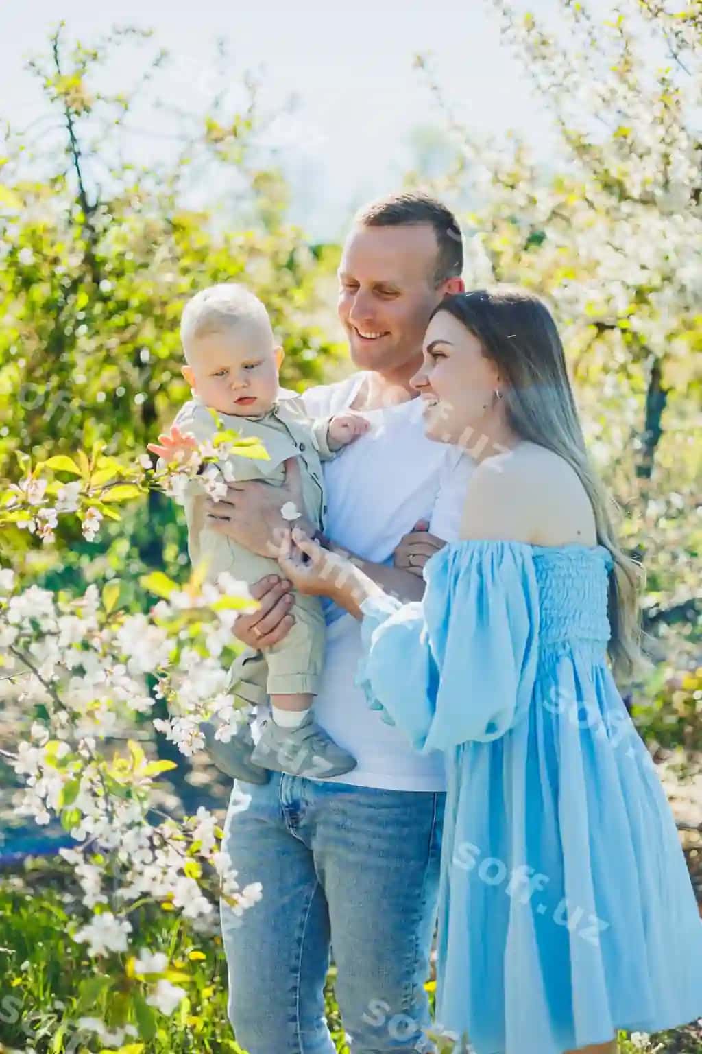 Baxtli oila juftigi bolasi bilan gullagan bog'da yurmoqda. | Happy family couple with child walk blooming garden