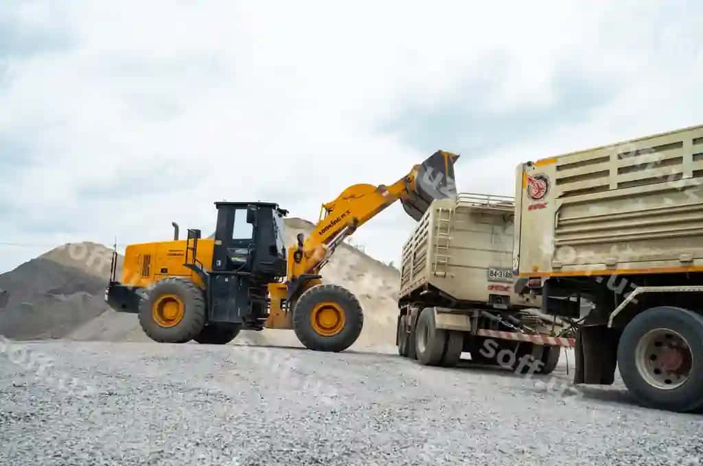 Qum yuklovchi moshinalar toshlarni dump trucklarga qozonmoqda. | Sand loaders are shoveling rocks into dump trucks