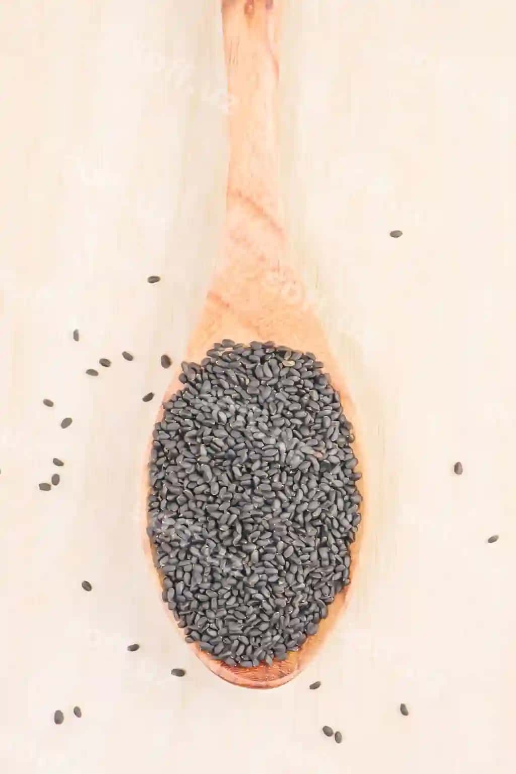 Vertikal rasm bazarb urug‘lari, yog‘och qoshiq, yog‘och stol orqa fonda | Vertical shot basil seeds wooden spoon wooden table background