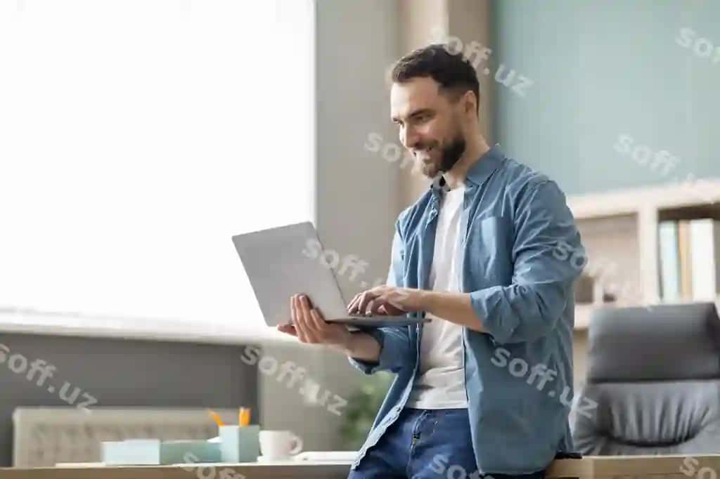 Portret gulovchi yosh biznesmen noutbuk ishlatgan holda zamonaviy ofis ichki ko'rinishida | Portrait smiling young businessman using laptop modern office interior