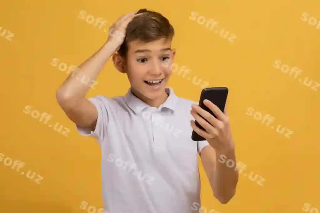 Hayratlangan yosh bola akillik telefon ekraniga qarab boshini tegmoqda. | Amazed teen boy looking smartphone screen touching head